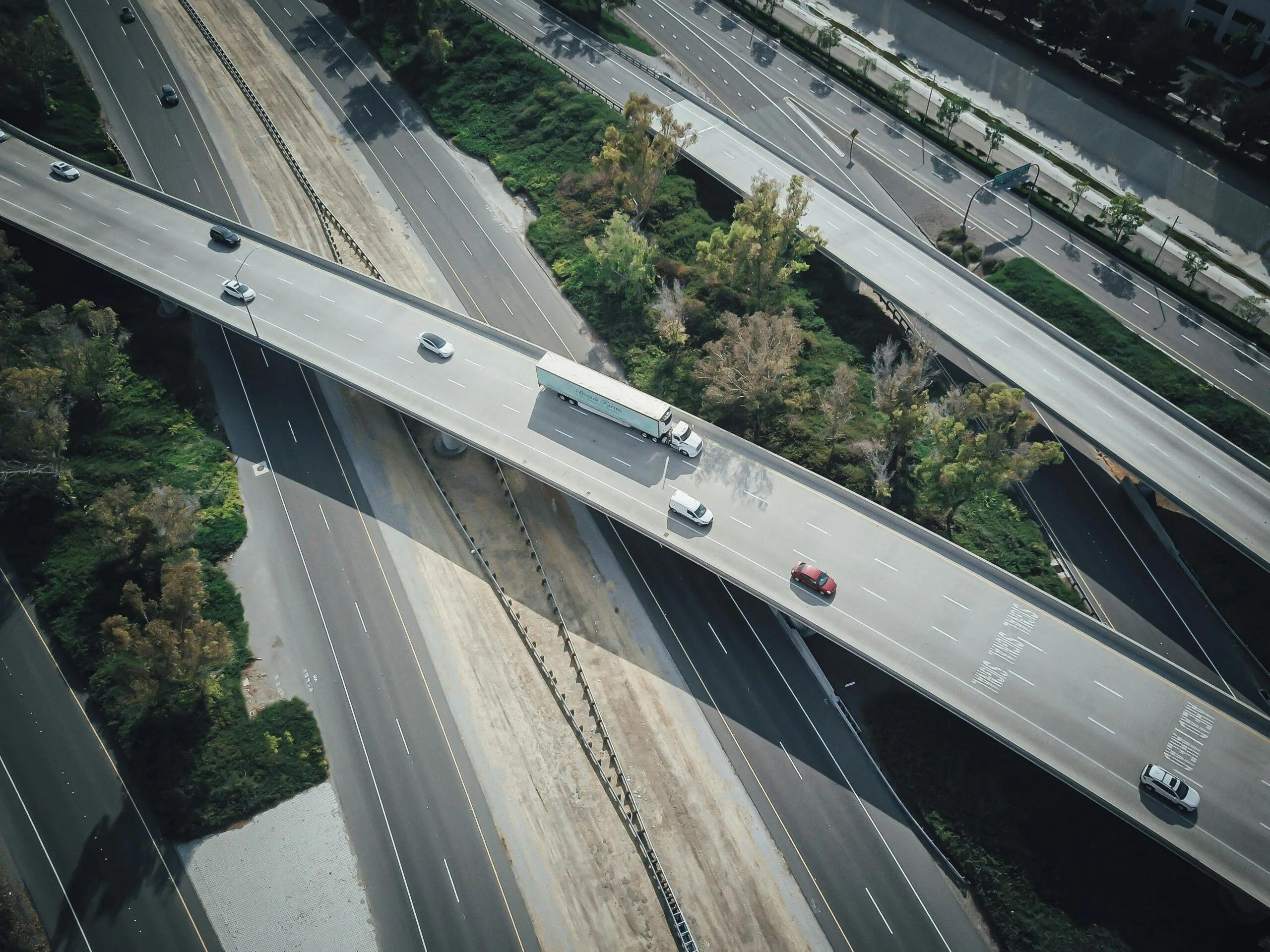 Solution 1 Aerial view of a highway with vehicles and a white truck on an overpass.